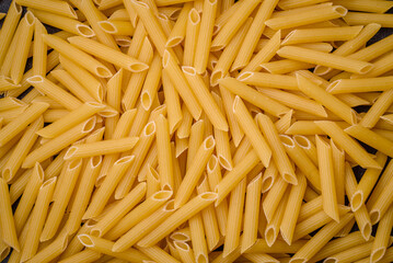 Raw penne pasta from whole grain wheat varieties with salt and spices