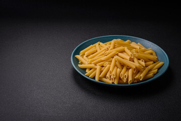 Raw penne pasta from whole grain wheat varieties with salt and spices