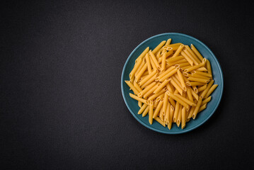 Raw penne pasta from whole grain wheat varieties with salt and spices