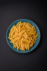 Raw penne pasta from whole grain wheat varieties with salt and spices