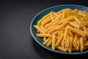 Raw penne pasta from whole grain wheat varieties with salt and spices