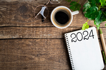 New year resolutions 2024 on desk. 2024 goals list with notebook, coffee cup, plant on wooden...