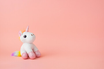 A toy unicorn on a pink background. Copy space