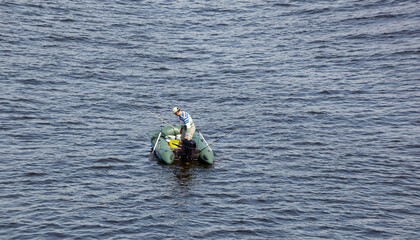 Mature man fishing on the lake from rubber inflatable boat. Fishing on the river. Natural river background