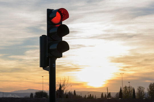 Sem&aacute;foro de tr&aacute;fico en rojo con fondo de puesta de sol 
