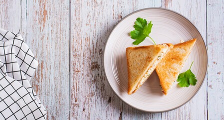 Bacon, egg and herb salad in a trendy chopped grilled sandwich on a plate top view web banner