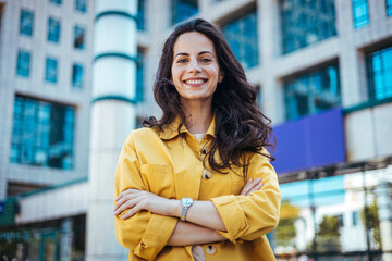 Portrait of a confident young businesswoman standing against an urban background. Portrait of...