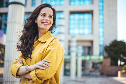 Portrait of a confident young businesswoman standing against an urban background. Portrait of carefree young woman smiling and looking at camera with urban background.