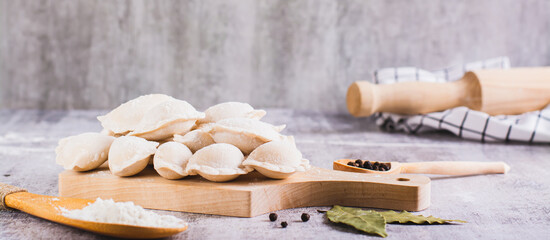 Homemade raw dumplings with meat on a cutting board on the table web banner