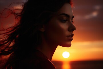 A picture of a woman with long hair standing against a backdrop of a beautiful sunset. This image can be used to depict tranquility, beauty, and serenity.