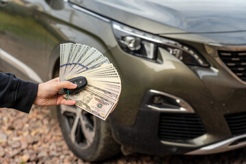 Person with money and car key standing front car. Insurance, loan concept. Deal of buy or rent new...