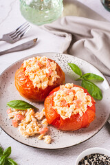 Eggs baked in ripe tomatoes and basil on a plate on the table vertical view