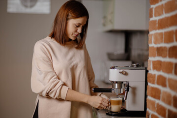 Beautiful woman preparing coffee in coffee machine at home