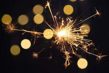 Burning sparkler with golden bokeh light background. New year party background. New year sparkles.