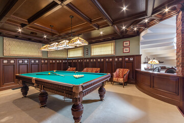 The interior of the billiard room in the English style. The room is decorated with .dark wood....