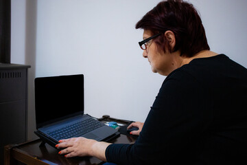 Older woman with red hair using a laptop with a blank screen