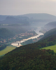 Fototapeta na wymiar Aerial view of Bad Schandau in Saxon Switzerland in the early foggy morning, Carolabrücke bridge on the Elbe river, sandstone rocks and mountains