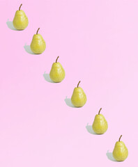 Yellow pears diagonally lined up against pink background. Minimal fruit concept. Geometric pattern....