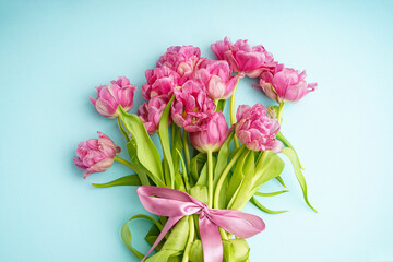 Fresh pink peony tulips on pastel blue background, top view. Festive concept for Mother's Day or Valentines Day.