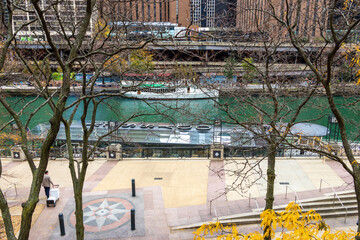 A beautiful autumn landscape along the Chicago River with yellow autumn trees, boats on the water and skyscrapers and hotels along the banks in Chicago Illinois USA
