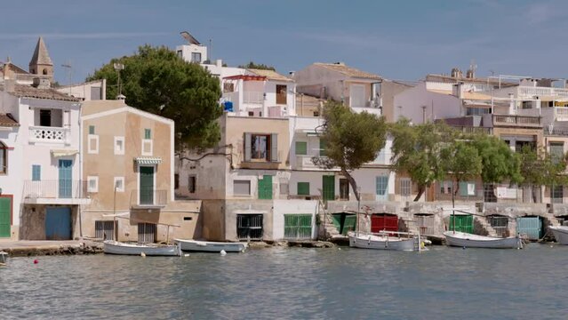 a long shot of fishing boats and houses at the harbor of portocolom on mallorca, spain