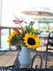 sunflowers in a vase on a table near the sea