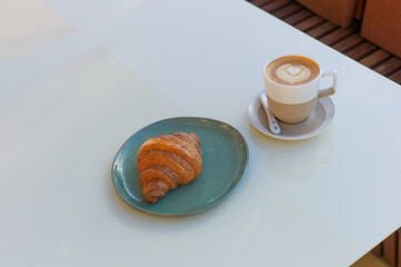 Cappuccino and croissant at an outdoor cafe