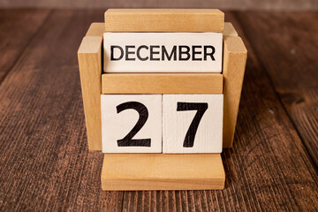 Cube shape calendar for December 27 on wooden surface with empty space for text,