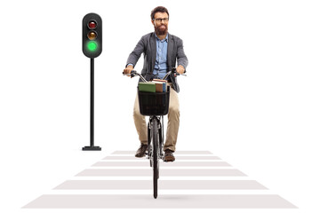Man on a bicycle crossing a street at green traffic light