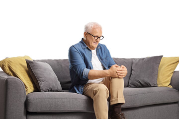 Mature man sitting on a sofa and holding his knee