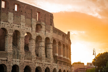 Early morning view of the colosseum in Rome, red and blue skies with sun just about to rise above the great famous amphitheatre. Autumn setting.