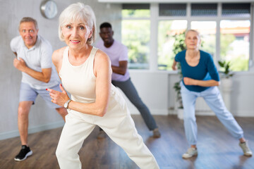 Cheerful sporty elderly woman having fun and dancing hip hop during workout in group dance class for adults