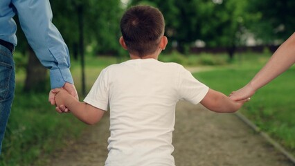 Child, Mother, father, family runs. Child son walks with mom dad in park holding hands. Happy family with baby boy walking outdoors, summer. Parents child go together, family weekend. Boy kid, dad mom