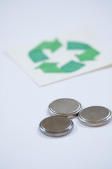 closeup of three button batteries next to recycling symbol