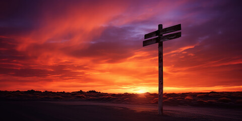 The stark silhouette of a signpost on a deserted road under the dramatic hues of a sunset sky