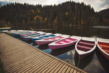 Boats on majestic mountain lake Lacul Rosu or Red Lake or Killer Lake. Splendid autumn scene of...