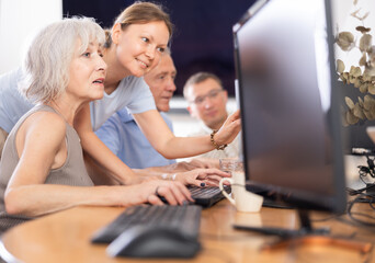 Curious mature woman engaged in IT training with help of teacher in computer courses