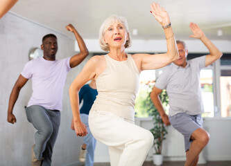 Cheerful elderly woman attending group choreography class, learning modern dynamic dances. Concept of active lifestyle of older generation