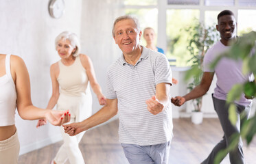 Group of multinational sports aged people rehearsing modern dance in dance hall