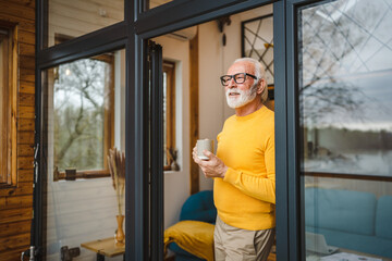 One senior man stand in at door of tiny house happy smile hold cup