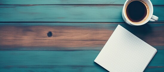 Coffee cup, notepad, and pen on office desk, seen from above.