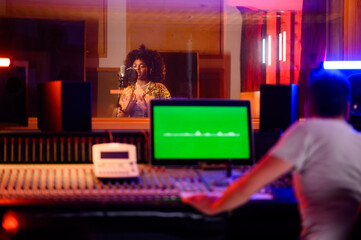Fototapeta na wymiar Talented multicultural singer recording in vocal isolation booth in music studio.