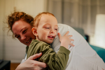 A happy child is hugging his friendly pediatrician during her visit at home.