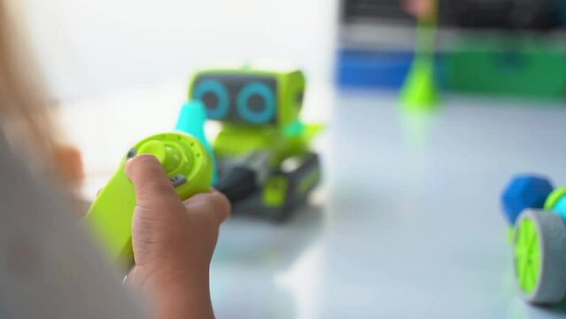 Close up hands of school child Elementary age kids playing with joystick controlling driving electronic toy car at home. Children hobby, development, education, fine motor skills
