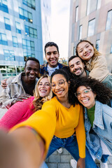 Young adult diverse friends smile at phone camera on selfie group portrait. Teenage community concept with joyful millennial students having fun together at city street.
