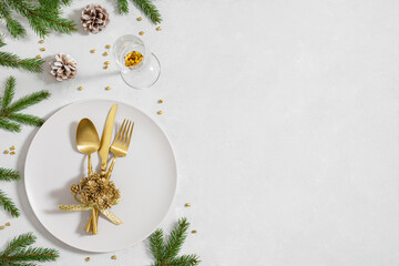 Christmas table setting with fir branches, golden decorations and cutlery on white background with...