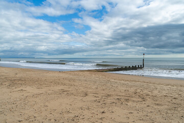 Fototapeta na wymiar Bournemouth, UK - March 26th 2023: Waves alongside a groyne on Bournemouth Beach.
