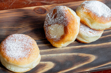 Berliner doughnuts with strawberry jam close-up on a wooden stand