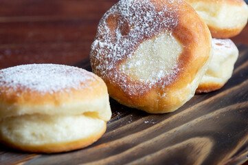Berliner doughnuts with strawberry jam close-up on a wooden stand