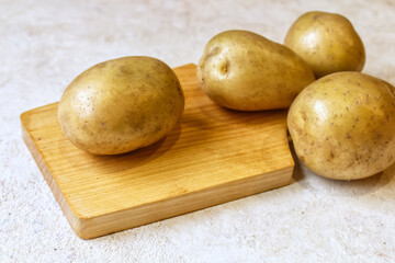 Washed, fresh, raw, new potatoes on a wooden board, light background.